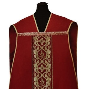 May include: A red liturgical vestment with gold embroidery featuring a vine and wheat design. The vestment has a wide, gold-trimmed collar.