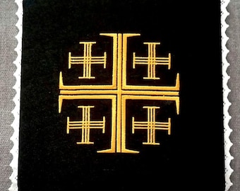 May include: A black velvet kneeling pad with a gold embroidered cross. The cross is a traditional design with four arms and a central circle.