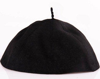 May include: A solid black hat with a rounded crown and a small, braided detail at the top. The hat appears to be made of a textured fabric and is set against a white background.
