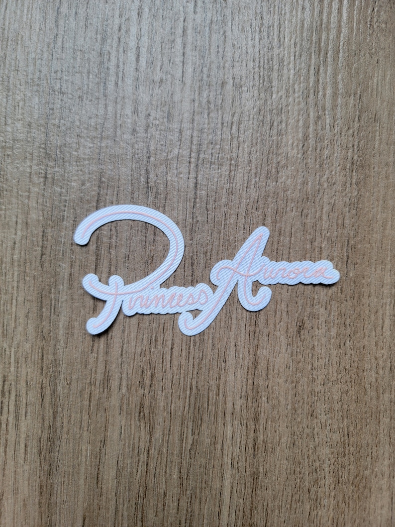 May include: White sticker with pink lettering that says "Princess Aurora".