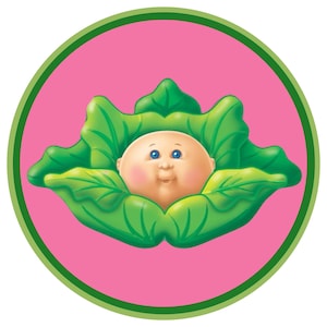 May include: A round graphic featuring a baby-like face with blue eyes and rosy cheeks nestled in green cabbage leaves. The image is set against a pink background, framed by a green border.
