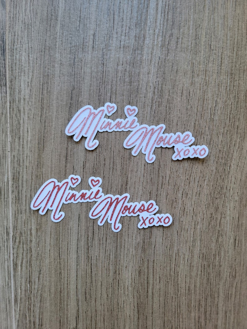 May include: Two white stickers with pink glitter lettering that reads "Minnie Mouse xoxo".