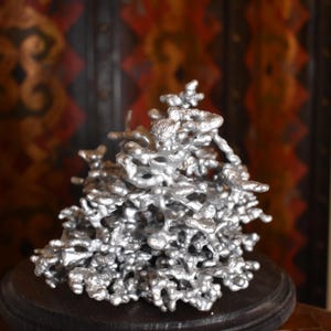 May include: A silver-colored metal sculpture featuring an intricate, organic, and branching structure with numerous interconnected nodes and porous, irregular shapes that create a complex, three-dimensional form with a metallic, reflective finish.