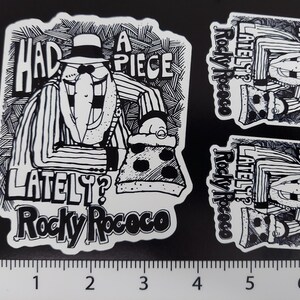 May include: Black and white sticker featuring a cartoon character wearing a hat and holding a slice of pizza. The text on the sticker reads "Had a piece lately? Rocky Rococo".