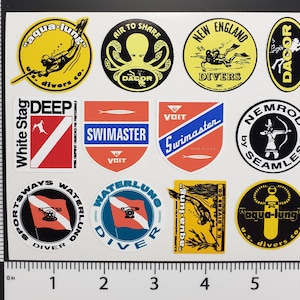 May include: A sheet of vintage diving stickers featuring various logos and designs. The stickers include the "Aqua-Lung" logo, "Air to Share" with an octopus, "New England Divers," and "Swimaster." The stickers are in various colors, including yellow, red, and blue.