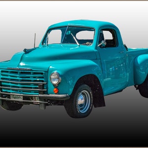 Könnte beinhalten: Ein blauer Vintage-Pickup mit Chromstoßstange und schwarzem Kühlergrill. Der Hintergrund ist weiß.