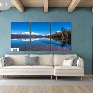 May include: A three-panel canvas print of a mountain lake with snow-capped mountains reflected in the water. The print is labeled "3x6" and is displayed in a living room setting with a white couch and a wooden door.
