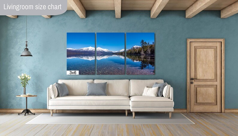 May include: A three-panel canvas print of a mountain lake with snow-capped mountains reflected in the water. The print is labeled "3x6" and is displayed in a living room setting with a white couch and a wooden door.