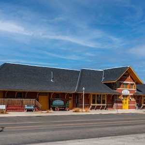 May include: A brick building with a yellow trim and a black roof. The building has a sign that says "Museum" and another sign that says "Old Depot Theatre".