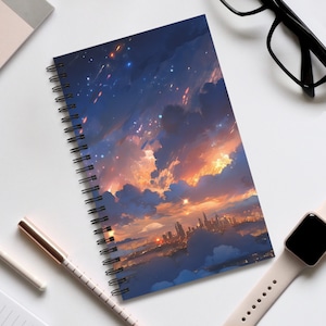 Op de afbeelding: Een spiraalgebonden notitieboek met een kleurrijke illustratie van een stadsbeeld bij zonsondergang met een sterrenhemel. De illustratie toont een stadsbeeld met hoge gebouwen, wolken en een heldere oranje zonsondergang.