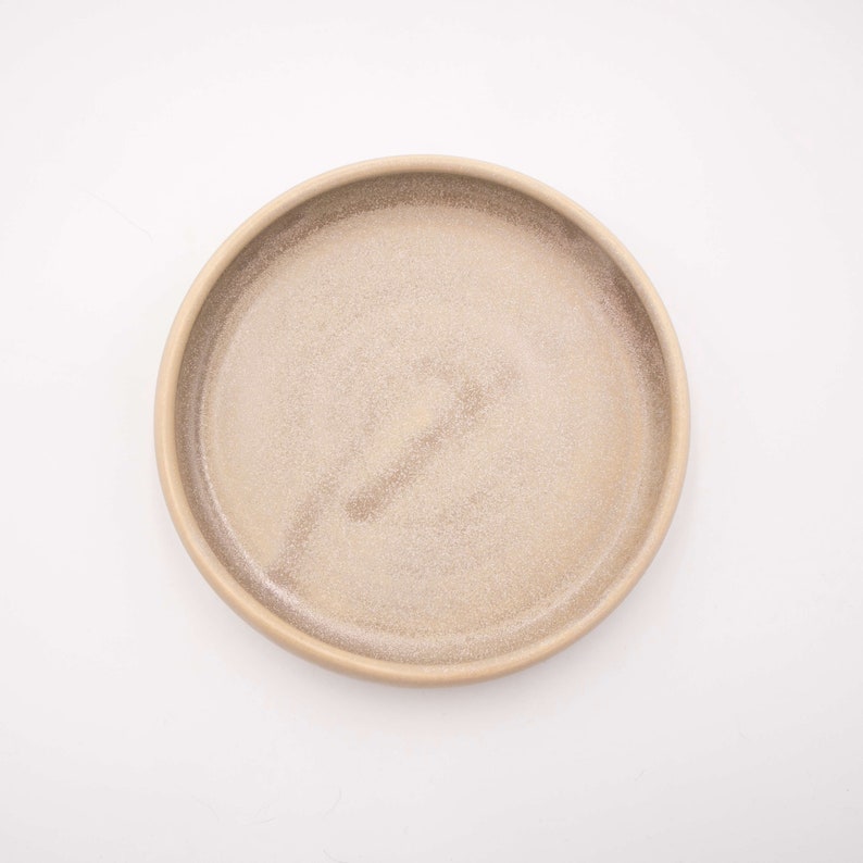 Der Futternapf besteht aus Keramik und hat die ideale Größe. Der Rand ist sehr niedrig um die Schnurrhaare der Katzen nicht zu stören. Die Farbe ist ein natürliches Creme mit schönen scheinenden Akzenten.