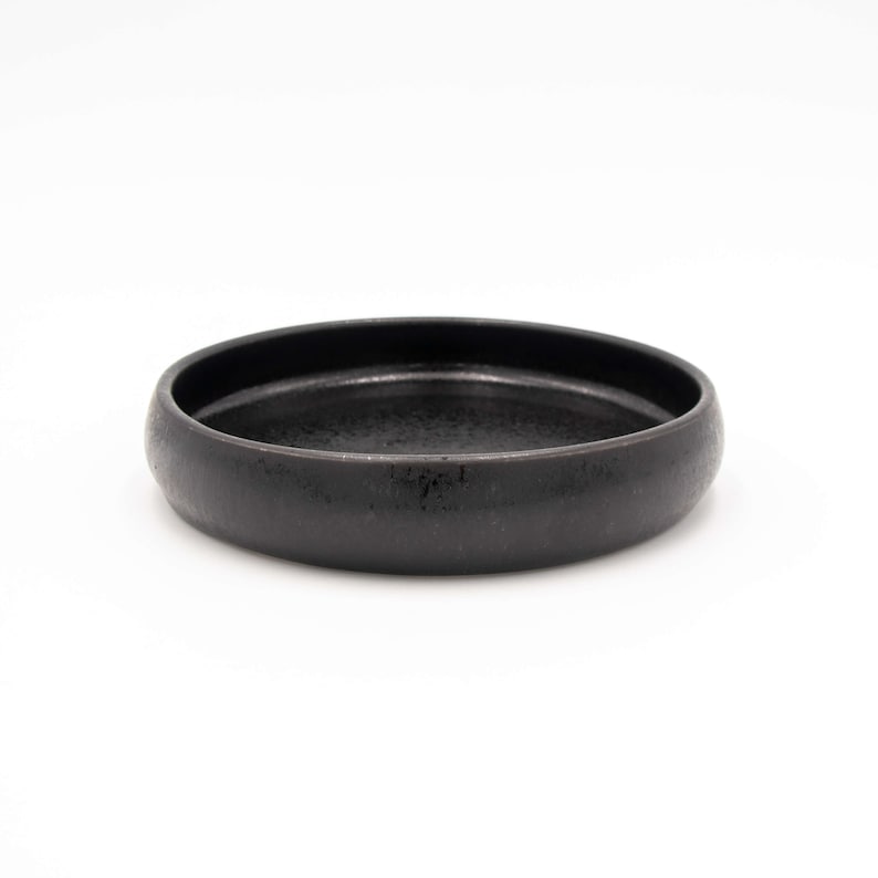 Der Futternapf besteht aus Keramik und hat die ideale Größe. Der Rand ist sehr niedrig um die Schnurrhaare der Katzen nicht zu stören. Die Farbe ist ein schönes Schwarz mit schimmernden Akzenten.