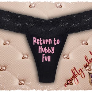Op de afbeelding: Zwarte string met een kanten rand. De tekst "Return to Hubby Full" is roze gedrukt. De achtergrond is een gewatteerde, beige stof met parelachtige knopen. De woorden "naughty eclectics" zijn geschreven.