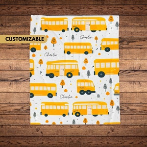 May include: A white background with a repeating pattern of yellow school buses, gray trees, and orange dots. The text "Charlie" appears multiple times on the fabric.