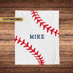 Op de afbeelding: Witte baseballdeken met rode stiksels en de naam "MIKE" in blauwe tekst.