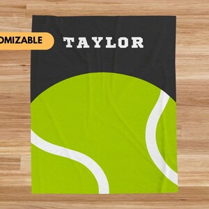 May include: A black and green fleece blanket with a white tennis ball and the name "TAYLOR" in white text.