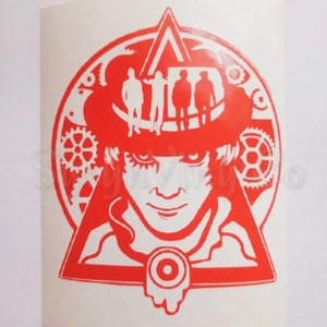 May include: Red and white vinyl decal featuring a stylized image of a man with a top hat and a triangle. Four figures are standing on top of the hat. The image is surrounded by gears and a circle.
