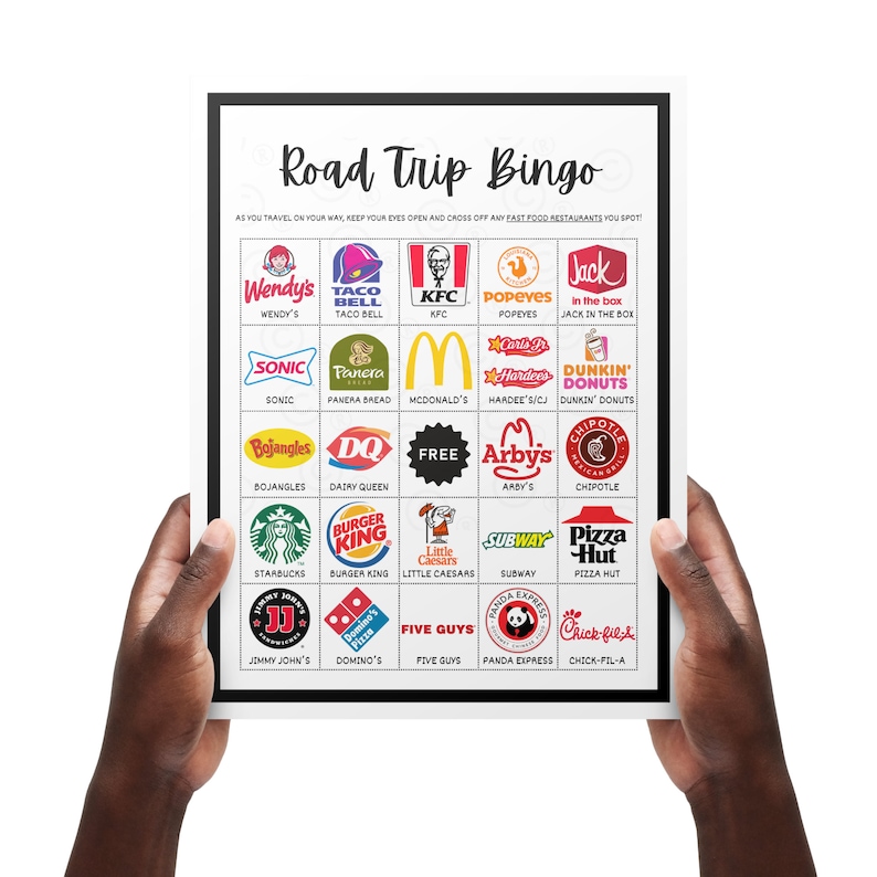 May include: A white framed "Road Trip Bingo" game board featuring fast food restaurant logos. Includes Wendy's, Taco Bell, KFC, Popeyes, Sonic, Panera Bread, McDonald's, Hardee's, Dunkin' Donuts, and more. Held by two hands.