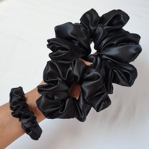 Photo of the set of all 3 scrunchies sizes placed together on the palm of the hand to show the size comparison to each other.