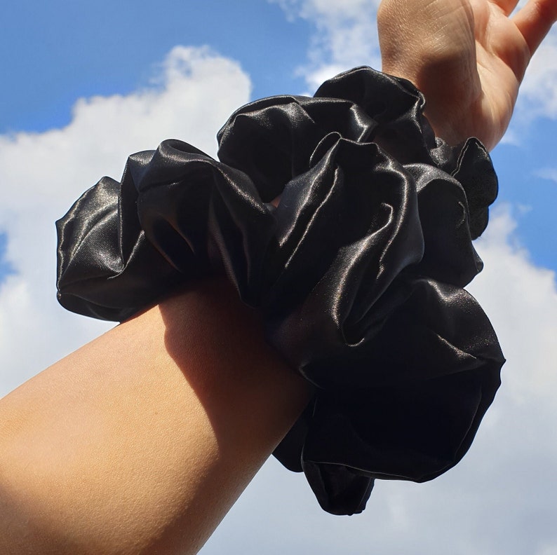 Photo of the set of all 3 scrunchies sizes worn on the wrist as a fashion accessory.