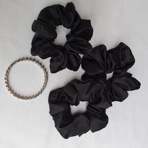 Photo of 3 medium black satin scrunchies placed together next to a bangle for size reference