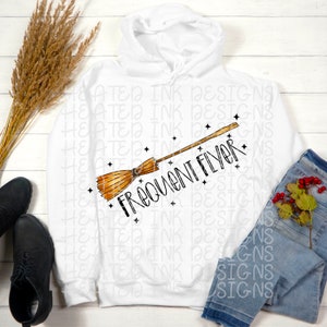 以下が含まれることがあります： 白いフード付きスウェットシャツに、黒と金のほうきと「Frequent Flyer」という文字がプリントされています。