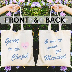 May include: Two white tote bags with blue text. The front bag says "Going to the Chapel" with a pink heart that says "Future Mrs. Johnson". The back bag says "& we're gonna get Married".