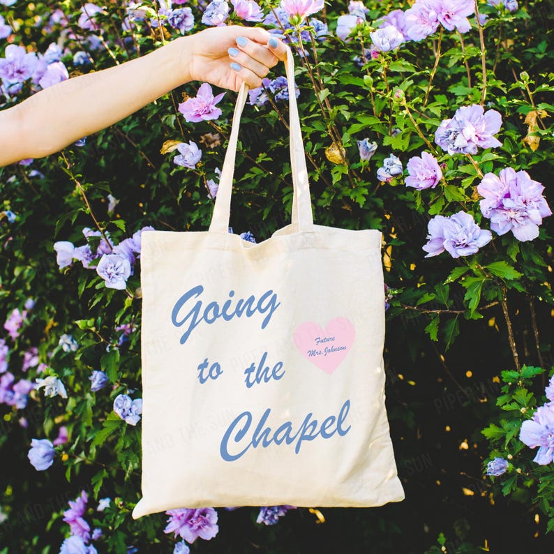 May include: A white tote bag with the text "Going to the Chapel" in blue script. A pink heart with the text "Future Mrs. Johnson" is on the bag.