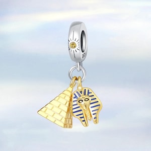 May include: Silver charm with a gold pyramid and a blue and gold pharaoh head pendant. The charm has a clear stone in the center.
