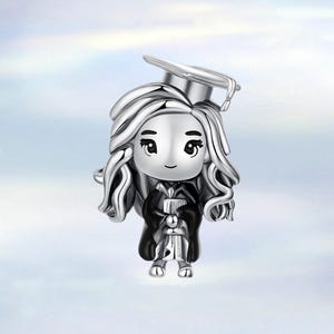 Könnte beinhalten: Ein silberner Charm-Anhänger, der einen Absolventen in Hut und Robe darstellt. Der Anhänger zeigt eine stilisierte Figur mit langem, fließendem Haar, einer Abschlusskappe und einer schwarzen Robe. Die Figur hält eine Schriftrolle, die akademischen Erfolg symbolisiert.