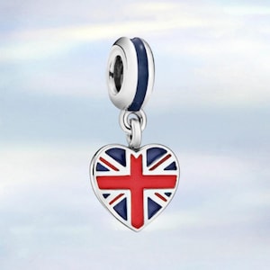 May include: A silver charm with a heart-shaped pendant displaying the Union Jack flag. The charm has a blue and red enamel finish, with a loop at the top for attachment to a bracelet or necklace.