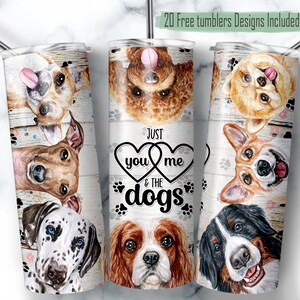 May include: A set of three stainless steel tumblers featuring a design with various dog breeds and the text "Just you me & the dogs". The tumblers have a white wooden background with paw prints.