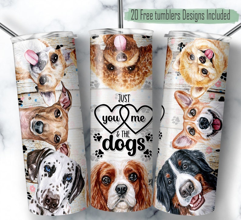 May include: A set of three stainless steel tumblers featuring a design with various dog breeds and the text "Just you me & the dogs". The tumblers have a white wooden background with paw prints.