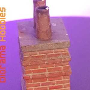May include: A miniature brick chimney with two brown chimney pots. The chimney has a weathered appearance, with a gray top and a red brick base. The text "Diorama Hobbies" is printed vertically in orange.