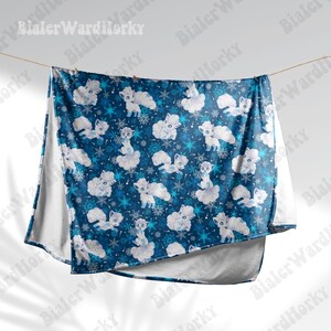 May include: A blue blanket featuring a pattern of white cartoon foxes, snowflakes, and clouds. The blanket is hanging from a washing line. The blanket has a white border.