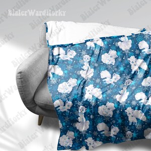 May include: A blue blanket featuring a pattern of white cartoon foxes, clouds, and snowflakes. The blanket is draped over a gray armchair. The top edge of the blanket is white.
