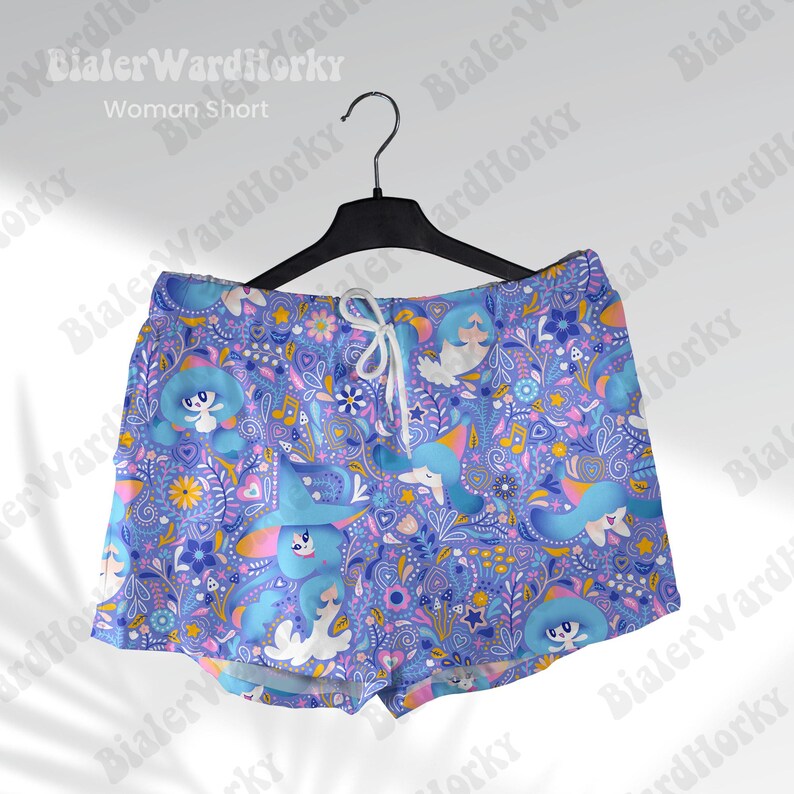 May include: Blue shorts with a whimsical pattern of cartoon characters, flowers, and musical notes. The shorts have a drawstring waist and are hanging on a black hanger. The text "Woman Short" is visible.