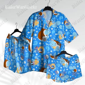 May include: A short-sleeve button-down shirt and two pairs of shorts featuring a repeating pattern of light blue turtle-like creatures with brown shells, white water droplets, and small red and white spherical icons on a bright blue background.