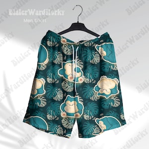 May include: Teal shorts with a repeating pattern of a cartoon character and tropical leaves. The shorts have a drawstring waist and are hanging on a black hanger. The text "Men Short" is visible.