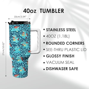 May include: A 40oz tumbler with a blue and green cartoon alligator pattern. The tumbler has a white handle and a black lid. The text "40oz TUMBLER" is at the top. The tumbler is 27cm tall and 10cm wide.