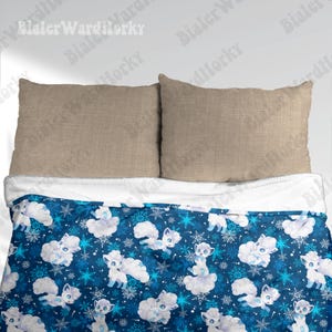 May include: A blue blanket with a white sherpa lining, patterned with white cartoon foxes and snowflakes. Two beige pillows are positioned above the blanket, creating a cosy bedding arrangement.