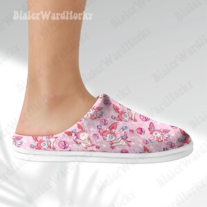 Może przedstawiać: R&oacute;żowy kapcie z wzorem postaci z kresk&oacute;wek. Kapcie mają białą podeszwę i r&oacute;żową cholewkę z powtarzającym się wzorem postaci, gwiazd i bąbelk&oacute;w. Kapcie są przeznaczone do użytku w pomieszczeniach.