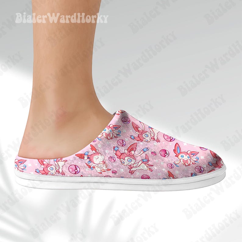 Może przedstawiać: R&oacute;żowy kapcie z wzorem postaci z kresk&oacute;wek. Kapcie mają białą podeszwę i r&oacute;żową cholewkę z powtarzającym się wzorem postaci, gwiazd i bąbelk&oacute;w. Kapcie są przeznaczone do użytku w pomieszczeniach.