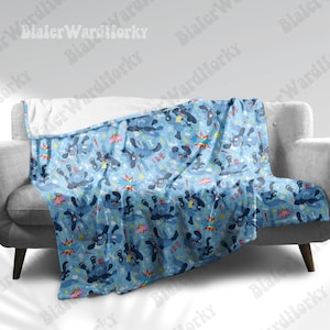 May include: A light blue throw blanket with a repeating pattern of cartoon dogs, bones, and comic book-style sound effects. The blanket is draped over a gray sofa, showcasing its design and texture. The blanket's design includes the words "HA HA" and "WOW".