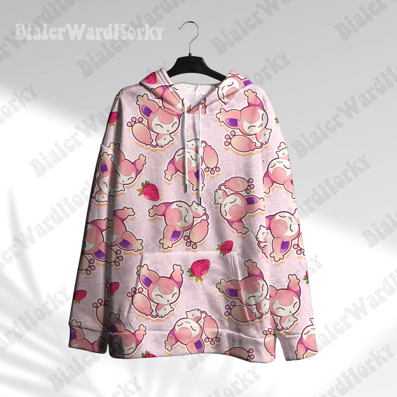 May include: A light pink hoodie with a repeating pattern of cartoon characters and strawberries. The characters are primarily pink and white with purple accents. The hoodie has a drawstring and is hanging on a black hanger.