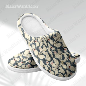 May include: Pair of plush slippers with a repeating pattern of cartoon characters in beige and red on a dark blue background. The slippers have a white trim and a soft, white interior.