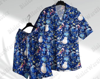 Puede incluir: Un conjunto a juego de camisa y pantalones cortos azules de manga corta. El conjunto presenta un patrón repetido de personajes de dibujos animados en tonos de azul, blanco y otros colores. La camisa tiene cuello en V y los pantalones cortos tienen cordón.