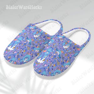 Puede incluir: Un par de zapatillas estampadas en azul y morado con interior blanco. Las zapatillas presentan un diseño caprichoso con personajes de dibujos animados, flores y elementos de cachemira. Diseñadas para uso en interiores.