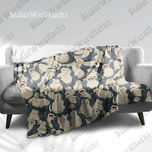 Può includere: Una morbida coperta beige e blu con un motivo ripetuto di personaggi dei cartoni animati Snorlax. La coperta è realizzata in un materiale morbido e peluche ed è perfetta per coccolarsi sul divano.
