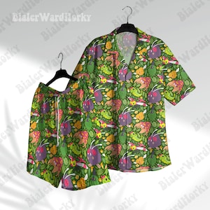 May include: A matching green button-down shirt and shorts set. The set features a repeating pattern of cartoon-like creatures in shades of purple, yellow, and green, set against a background of green foliage. The shirt has short sleeves and a collar, while the shorts have a drawstring.
